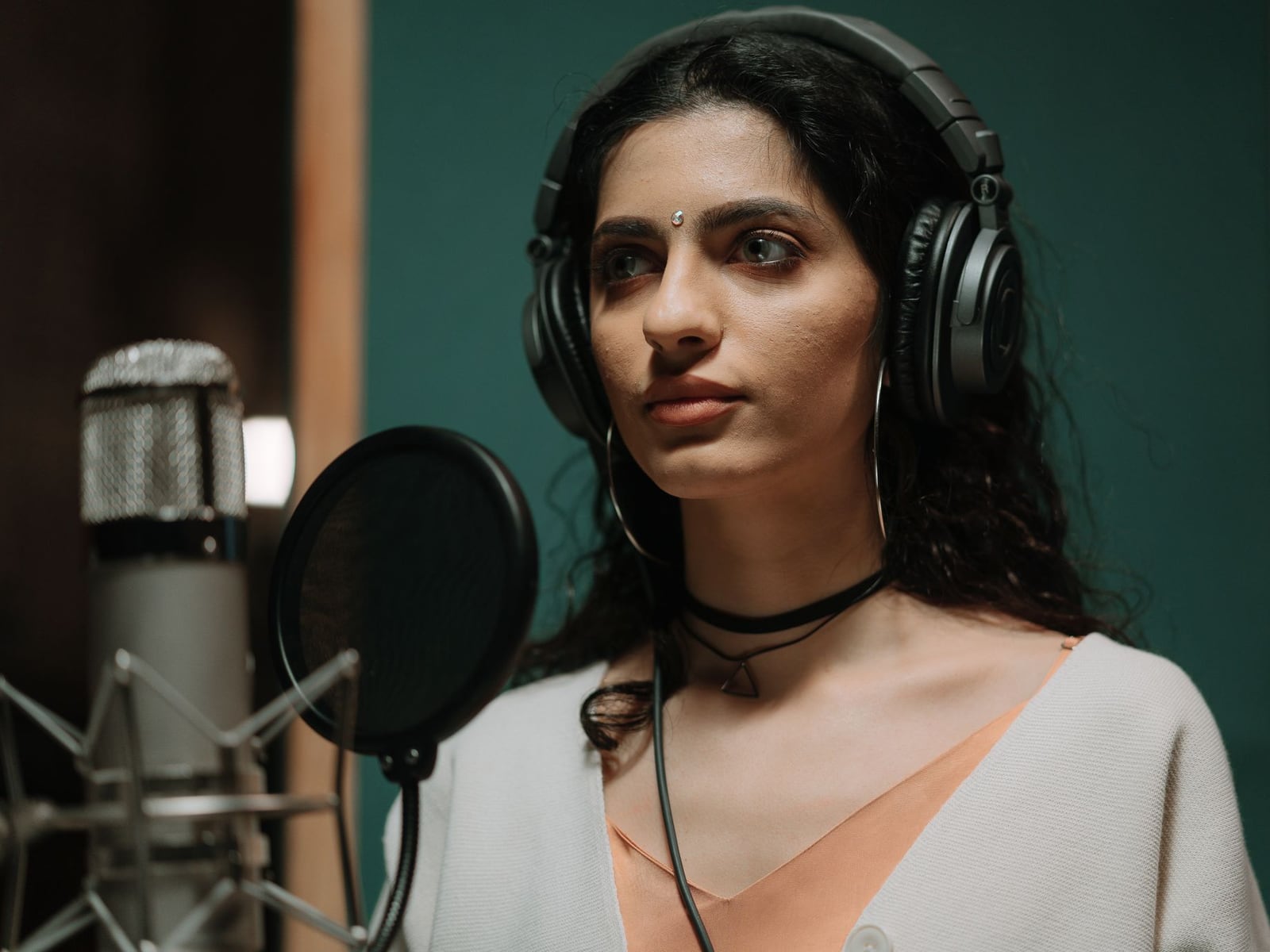 A singer recording vocals in a soundproof booth with a professional condenser microphone